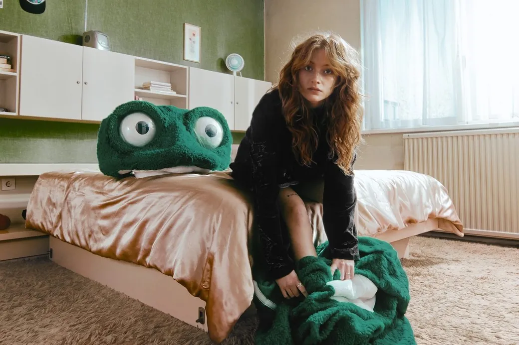 Froukje in a bedroom with a green frog costume.